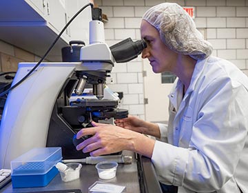 Lab tech looking through microscope